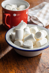 White sweet marshmallows candy in mug on a kitchen table.