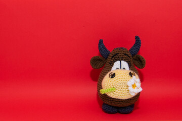 brown knitted handmade bull on the red background, symbol of 2021 year, bull