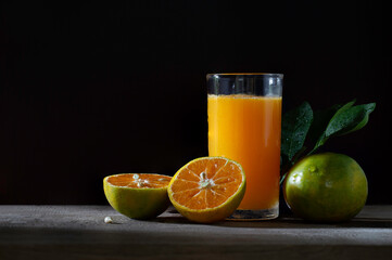 Fresh Tangerine and Orange juice in glass on wooden floor