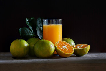 Fototapeta premium Fresh Tangerine and Orange juice in glass on wooden floor