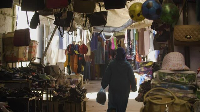 Muslmim women is walking in a typical souk (market) in Morocco, lot of colors.