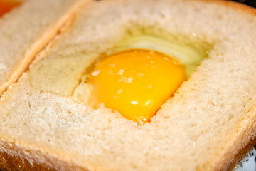 Making the sandwich of the bread and raw eggs. A hearty toast for Breakfast.