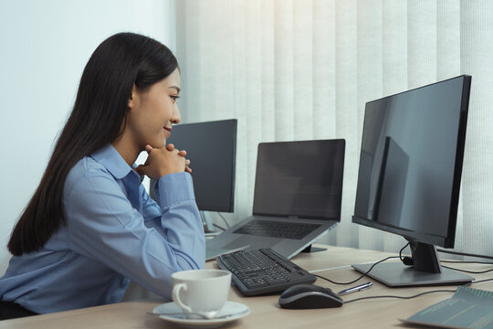 Asian woman software developers sitting in front of computers looking at computer codes on the screen.