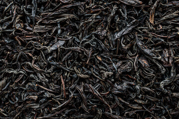 black dry large leaf tea as background texture, selective focus