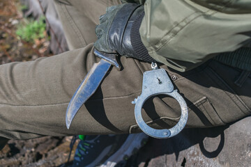 Fototapeta na wymiar Combat knife and handcuffs in the hands of a fighter close-up