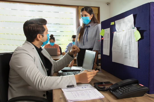 OFFICE EXECUTIVES WEARING MASK AND DISCUSSING WORK WITH EACH OTHER	