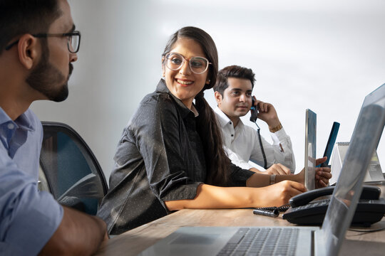 AN OFFICE EXECUTIVE TALKING TO COLLEAGUE WHILE WORKING IN OFFICE	
