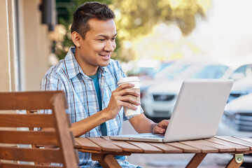 Malaysian man drinking coffee and using laptop at cafe