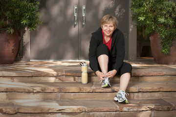Woman tying athletic shoes before exercising
