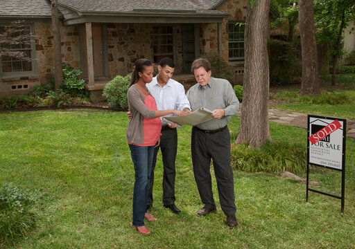 Couple standing with architect in yard of sold house