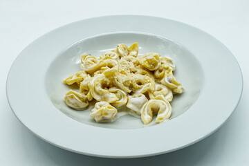 Tortellini alla panna with Parmigiano Reggiano cheese in a white dish. Traditional italian pasta. 