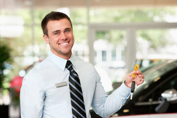 Caucasian man holding keys to new car in showroom