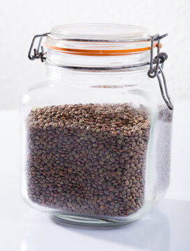 Dry Green Lentils In Glass Jar On White Background