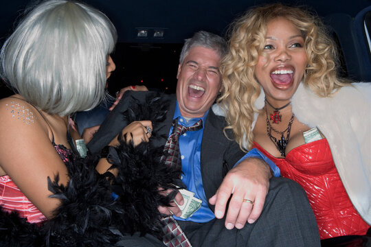 Middle-aged man and prostitutes laughing