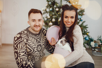 young and pretty couple sitting in a room near christmas tree with gifts