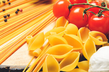 Uncooked pasta with vegetables on wooden background