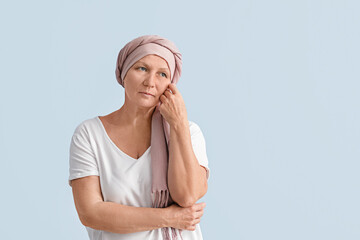 Sad mature woman after chemotherapy on light background