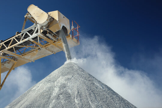 Details of rock stone crushing equipment in a limestone quarry against a dark blue sky, close-up.