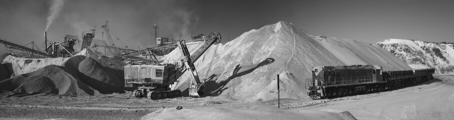 Rock stone crushing equipment, excavator, diesel locomotive in a mining enterprise, black and white panorama. Mining industry.