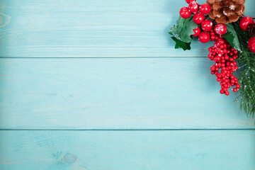 On a turquoise wood background, a decoration of a spruce branch and cones. Christmas background.