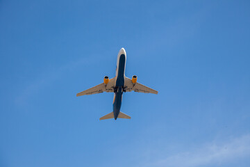 White plane flies in the sky. Bottom view. Takeoff and landing. Arrival and departure. Passenger plane isolated on blue background. Airplane flying. Travel by air transport. Copy space.