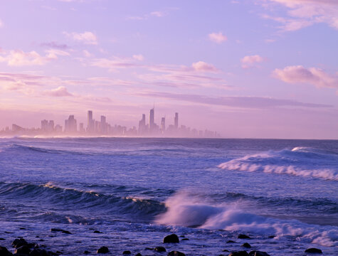 Looking across rolling waves and ocean at Surfers Paradise skyline of city