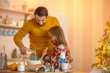 Girl and her dad stirring something in a bowl and smiling