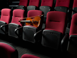 Violin resting on row of empty red auditorium seats