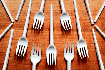 Some plastic forks placed on a wooden table.