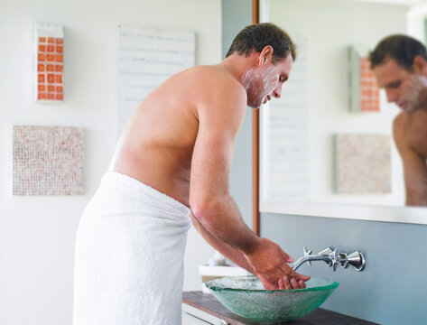 Man washing his hands after shaving in bathroom