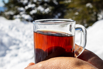 Hot tea in hand on the mountain, on a snowy and sunny day.
