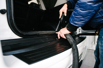 Man cleans car interior with vacuum cleaner