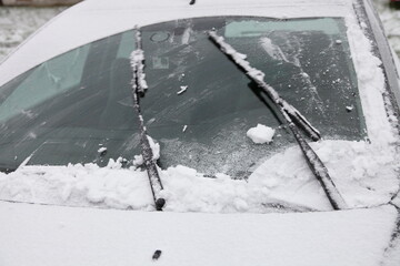 Wipers clean the car windshield from snow - winter, snowstorm icing vehicle after snowfall, safe winter driving, preparing for the trip