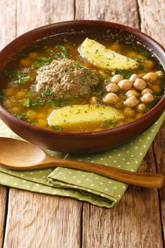 Homemade Kufta bozbash is a traditional Azerbaijani meatball soup and chickpea close-up in a plate on the table. Vertical