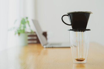 Unrecognizable man making a hand craft dripping coffee on the wooden table in the office during a break.