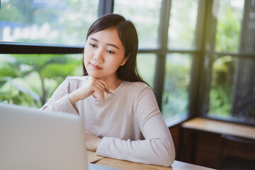 Happy Asian woman concentrated working in the coffee shop by using laptop computer.