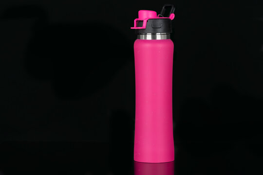 Close-up of colorful reusable, steel thermo water pink bottle, isolated on black background. Zero waste. Say no to plastic disposable bottle. Environment concept.