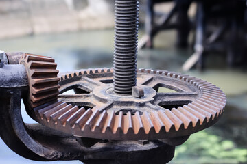 Rusty metal mechanical gear on the floodgate , old cogwheel background