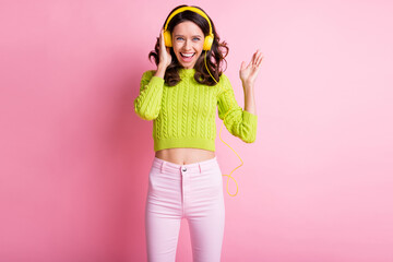 Obraz na płótnie Canvas Photo of lovely curly woman dressed green pullover dancing listening music headphones isolated pink color background