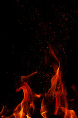 Fiery flame with sparks on a black background. Texture (element) for barbecue or cooking.