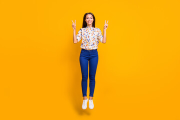 Full length photo portrait of woman showing two v-signs jumping up isolated on bright yellow colored background