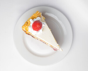 Piece of vanilla and chocolate cake with icing on white isolated background. Served on a white plate.