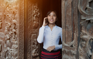 Closeup portrait of a beautiful Myanmar.woman With a smiley face, and using a smart phone