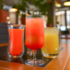 Three cocktails drinks on wooden table at bar indoors. Delicious fruit drinks for refreshment. Alcohol beverage.
