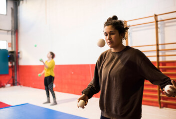 Woman working out in team in gym fiddling with balls training concentration