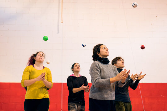 Group of women throwing up balls training skill and concentration standing in gym