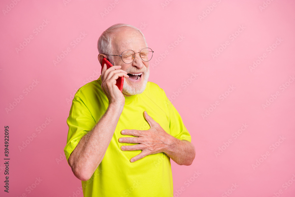 Sticker Photo of old happy smiling grandfather wear green t-shirt hold hand chest talk communicate speak phone isolated on pink color background