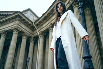 Naklejka premium Beautiful model girl woman on a background of old columns. Attractions behind the old cathedral
