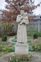  marble figure of a christian saint with Jesus on his hand on a gray sad autumn day