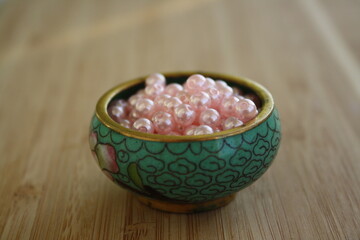 Fototapeta na wymiar Pink decorative beads on a glass transparent saucer.